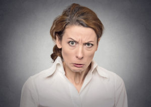 portrait of an angry grumpy funny looking woman isolated on gray wall background
