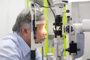 Asian senior male patient having him eyes examined by laser machine. Doctoroptometry concept.