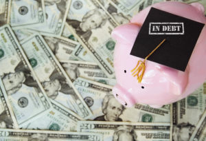 piggy bank with In Debt graduation cap on money